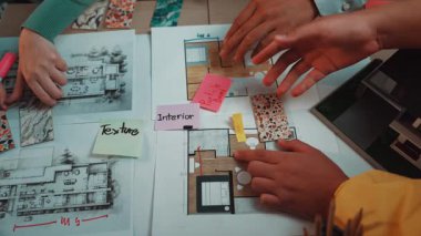 Ellerin hareketli bir iç tasarım oturumunda aktif olarak yer aldığı, masada canlı renk örnekleri, çizimler ve beyin fırtınası öğeleri gösteren dinamik bir sahne. SACTR