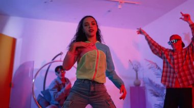 İspanyol hipster renkli kıyafetler giyer ve serbest stil müziğe el sallar. Profesyonel break dansçı neon ışıklarıyla ve modern stüdyo arkadaşlarıyla coşkuyla dans ediyor. Mutluluk.