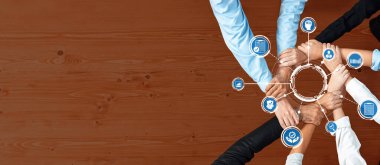 Ahşap bir yüzey üzerinde teknoloji ikonları etrafında birleşen canlı bir görsel gösterge, modern bir işyeri ortamında işbirliği, yenilik ve takım çalışmasını sembolize ediyor. Dostluk