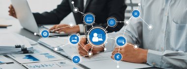 İki iş adamı bir ofis ortamında birlikte çalışarak, etkili bir işbirliği ve proje planlaması için dijital bağlantı ve veri analiz araçları sergiliyorlar. Dostluk