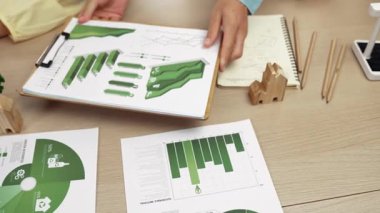 Şirketin gelecekteki EG 'si için yeşil enerji grafiği kullanımına danışmanlık ve analiz yapan iş ekibi. Yel değirmeni modeli, masadaki temiz enerji ve ev bloğu sembolize edilmiş eko evi kullanarak temsil ediliyor. Tanımlama.