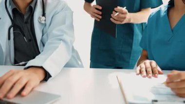 Hastane masasında birlikte çalışan ve tıbbi tedavi planlayan çeşitli profesyonel sağlık görevlileri. Takım çalışması başarılı hastalıklara ve hastalıklara yol açar. Ağır çekim. Katı.