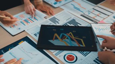 Çeşitli profesyonellerden oluşan bir grup, etkili iş stratejileri ve içgörüleri geliştirmek için ayrıntılı tablolar, grafikler ve dijital cihazlar hakkındaki raporları işbirliği içinde analiz ediyor. SACTR