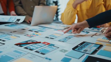 Çeşitli bir ekip, dijital cihazlar ve tasarım modellemeleriyle çevrili, modern bir iş ortamında yaratıcılığı ve işbirliğini teşvik eden bir beyin fırtınası oturumuna girişiyor. SACTR