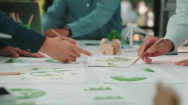 Çağdaş bir ofiste çalışan çeşitli profesyonellerden oluşan bir grup, gelecekteki proje ve girişimler için strateji oluşturan çevre çizelgeleri ve belgeleri analiz ediyor. SACTR