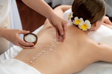 Lüks spa salonlarında sıcak mum ışığında cilt bakımı yaptıran kadın müşteri. Sağlık Spa vücut fırçasında tuz temizleme güzellik tedavisi. Sessiz.