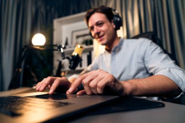 Sunucu kanalı akıllı yayıncı laptopta canlı sosyal medya uygulaması arıyor, kulaklık takıyor ve modern ofis stüdyosundaki mikrofonu kullanıyor. Bireysel.