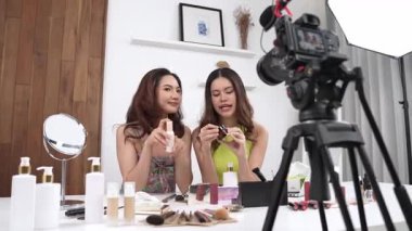 İki kadın nüfuzlu partner sosyal medya veya blog için canlı yayın yapan video klip inceleme derisi çekiyorlar. Canlı kozmetik stüdyo ışığı olan genç bir kız çevrimiçi pazarlama kayıt oturumu yayını için.