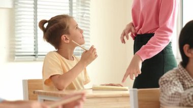 Beyaz bir çocuk ödevlerini yaparken ve açıklama dinlerken güzel bir öğretmen sınavı açıklıyor. Sınıfta not alırken ya da kağıda cevap yazarken öğretmenine bakan sevimli bir çocuk. Pedagoji.