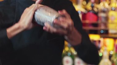 Yakın plan Asyalı barmen, özel bir içki menüsü hazırlamak için lüks tezgahta karışık kokteyl sallıyor. Gece hayatını gösteren özel bir içecek. Vinosity.