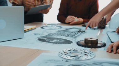 Makine tasarımı üzerinde çalışan mühendisleri gösteren dinamik bir sahne. Masada ayrıntılı çizimler, modern ekipmanlar ve canlı bir ofis atmosferinde işbirliği yer alıyor. SACTR