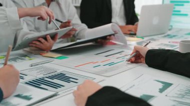 Uzmanlardan oluşan çeşitli bir ekip, bir ofis ortamında stratejik kararlar almak için veri analizi, grafikler ve grafikler üzerinde ortak bir tartışmaya girişiyor. SACTR