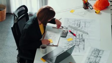 Zeki iş kadınlarının yürüyüşü ve ev tasarımı. Mimar mühendisinin güvenlik miğferi ve ev modeliyle birlikte binanın planına ve yapısına baktığı hava görüntüsü. Hizalama.