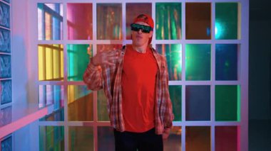 Serbest stil tişört giyerken sokak müziği çalan mutlu hipster. Gece kulübünde neon ışıkla dururken çekici break dansçı dans ve hareketli hareketler yapıyor. Mutluluk.