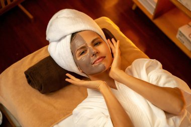 Kaplıca salonunun sakin atmosferi, üst düzey kadın müşteri sıcak mum ışığında kömür kömürü yüz kremi masajıyla kendini yenilemeye çalışıyor. Yüz bakımı ve güzellik konsepti. Sessiz.