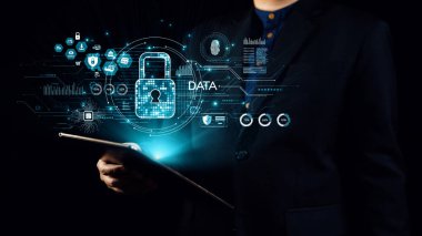 Bir işadamı, veri güvenliğinin önemini vurgulayarak siber güvenlik, veri koruması ve modern teknolojiyi temsil eden dijital simgelerle çevriliyken bir tablet tutuyor. Dörtgen
