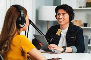 Gülümseyen radyo etkili sunucu elinde tablet, kulaklık takıyor kadın konuşmacı sosyal medya online canlı yayın kanalı ile röportaj yapıyor ve sabah stüdyo kaydında paylaşım linkini paylaşıyor. İnfobahn.