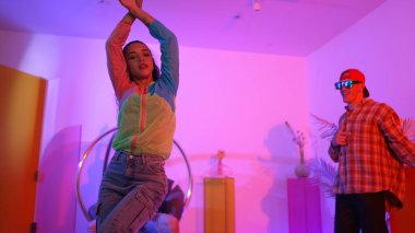 Çekici mutlu dansçı kameraya bakarken zeki kadın neon ışıkla kafiyeli hareket ediyor. Profesyonel İspanyol şarkıcı çeşitli arkadaşlarıyla renkli kıyafetler giyerken break dans yapıyor. Mutluluk.