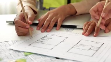 Mimari ekipmanlarla toplantı masasında ev tasarımı üzerine profesyonel mühendis ekibi tartışması ve modern ofiste bina planı dağılımı. Eline odaklan. - Yakın çekim. Tanımlama.