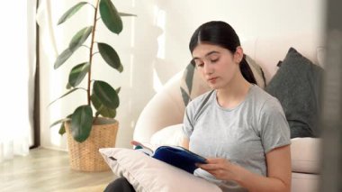 Kanepede oturan bir kadın ders kitabı okuyarak sosyal ve mesleki teknoloji bilgisini artırır ya da akıllı bir anne olmak için çocuk yetiştirir. Hayat boyu öğrenme konsepti. Uyumsuzluk.