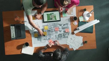 Bina planına bakarken inşaat mühendisinin elindeki belgelerin en alttaki görüntüsü. Mimarlık takımının fikir üretme ve planlama alanındaki hava görüşü masada planlı otururken. Sempozyum.