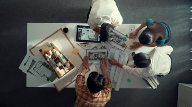 İç mimar tasarımcı dış tasarım hakkında konuşurken ve tartışırken mimar mühendis ekibinin yapışkan notlar yazıp ev modeline not yapıştırdığı yukarıdan aşağıya hava görüntüsü. Hizalama.