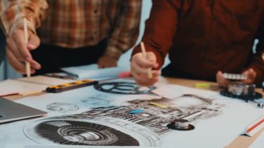 Dinamik bir ekip, teknik çizimlerle ilgilenen ve modern bir çalışma ortamında çeşitli taslak araçları kullanan bir mühendislik projesinde işbirliği yapar. SACTR