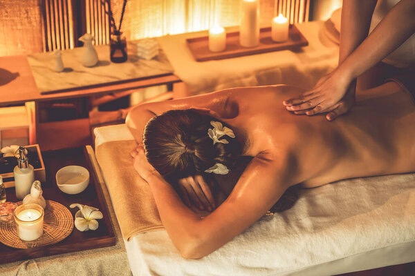 Caucasian woman customer enjoying relaxing anti-stress spa massage and pampering with beauty skin recreation leisure in warm candle lighting ambient salon spa at luxury resort or hotel. Quiescent