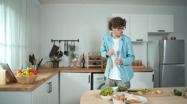 Mutlu baba yemek pişirirken müziğe geçiyor ve modern mutfakta öğle yemeği hazırlıyor. Aktif baba, sebze ve mutfak gereçleri ile çevrili sağlıklı yemek ya da salata yaparken şarkıyla dans ediyor. Pedagoji.