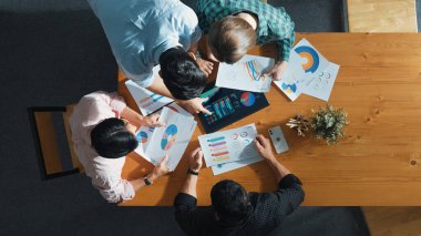 Akıllı iş adamlarının yukarıdan görünüşü toplantıda verileri analiz eder. Birlikte çalışan bir grup iş adamı ve toplantı masasına yerleştirilen tabletin mali tablosuna bakıyorlar. Cemaat.