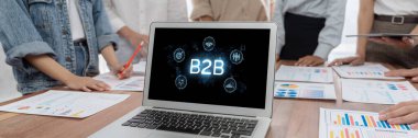 İş adamı B2B peyzajında geziniyor, iş-iş bağlantılarını geliştirmek için kullanım teknolojisi kullanıyor. B2B etkileşimini yeniden şekillendiren keşifler, iş-iş stratejilerinde yenilikleri yönlendiren araçlar. canlı