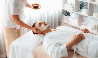 Kaplıca salonunun sakin atmosferi, insan müşterisi modern gün ışığında lüks yüz kremi masajıyla kendini yenileme zevkine kapılıyor. Yüz bakımı ve güzellik konsepti. Sessiz.