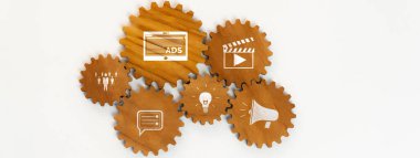 Bu resim, reklam, film üretimi, takım çalışması ve iletişim dinamiklerini temsil eden ikonları içeren birbirine bağlı ahşap dişliler içeren bir pazarlama stratejisi kavramını gösteriyor. Dostluk