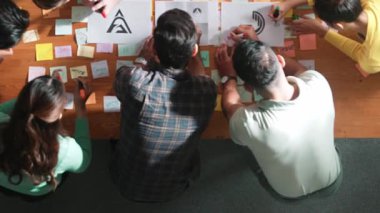 Ekiple tartışırken, yetenekli tasarımcı logosunun yukarıdan görünüşü. Hava ticareti grubu logo grafik tasarımı hakkındaki fikri yapışkan notlar ve tablet kullanarak paylaşıyor. Sempozyum.