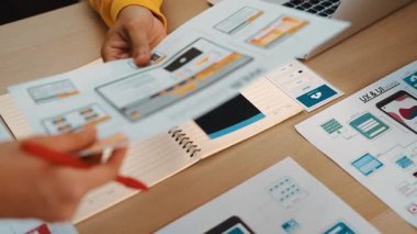 Mobil uygulama için kullanıcı arayüzü prototipini ofis çalışma alanındaki akıllı yöneticiye sunan mükemmel bir şirket çalışanı. UX UI tasarımcısı kağıt üzerinde simge tasarımının işlevini açıklıyor. Sinerjik