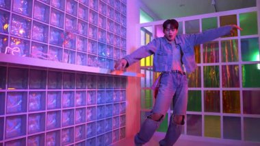 Çekici Asyalı sanatçı parlak neon ışıkta adım atıyor. Kameraya özgüvenle bakarken serbest stil müzikle dans eden yakışıklı break dans. Profesyonel hippi rahatla. Mutluluk.