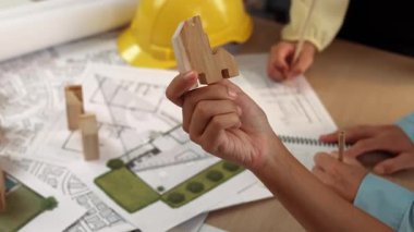 Mimar ve mühendis, mimari belge, ölçüm aracı ve ahşap bloğu ofis çevresinde dağıtan planlar kullanarak inşaat inşaatı hakkında düşünür veya tartışır. Tanımlama.