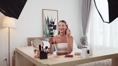 Sosyal medya için güzellik ve kozmetik video içeriği hazırlayan genç bir kadın. Güzellik blogcusu kameraya gülümserken seyircilere ve takipçilere güzellik bakımını gösteriyor. Düzenle