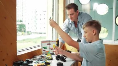 Kafkas öğretmeni öğrencilere araba modelini tamir etmede yardım ediyor ve liseli çocuklar STEM sınıfında robotu tamir etmek için ekipmanları dinlerken programlama sistemi ya da kodlama komutu veriyor. Öğretim
