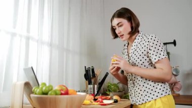 Kafkasyalı anne, modern mutfakta dizüstü bilgisayarda yemek tarifine bakarken salata yapmak için yemek hazırlıyor. Yetenekli ev bekçisi taze sebze kullanarak kahvaltı hazırlıyor. Pedagoji.