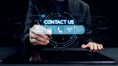 Bir iş adamı, e-posta ve telefon gibi iletişim seçeneklerini gösteren dijital bir arayüzle etkileşime girer. Görüntü, teknoloji meraklısı bir dünyada modern iletişimi gösteriyor. Dörtgen