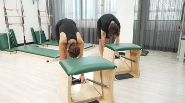 Müşteriler pilates antrenmanı sırasında ayakta gerinme egzersizi yapıyorlar. Esnekliği artırmak için. Spor salonunda bacak dayanıklılığı. Çekici grup esniyor ve eğiliyor. Alışkanlık.