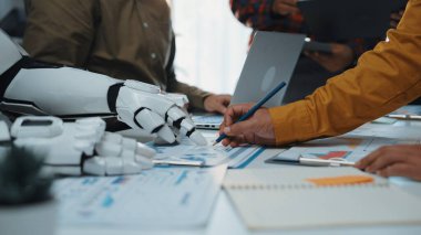 Bir insan ve robot arasındaki işbirliğini gösteren dinamik bir çalışma alanı, modern ofis ortamında teknoloji ve takım çalışmasının birleşimini vurguluyor. Noogenesis