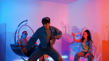 Çok kültürlü bir arkadaş kürsüde otururken Asyalı yetenekli bir dansçı modern müziğe geçiyor. Profesyonel dansçı, hipster takımı tezahürat yaparken ve desteklerken enerjik adımlar atıyor. Mutluluk.