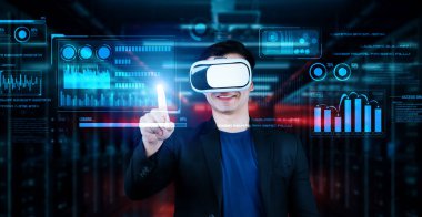 Finansal verileri analiz ederken veri merkezinde duran kulaklıklı bir iş adamı. Yönetici, pazarlama istatistiksel hologramını işaret ediyor ve karar verirken artırılmış gerçeklik gözlükleri kullanıyor. Yaratıcılık.