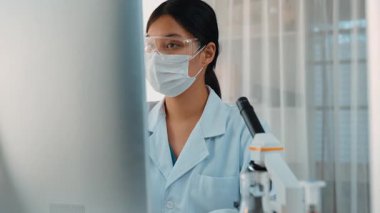 Laboratuvar kimya araştırmacısı mikroskop ve dizüstü bilgisayar kullanarak yeni ilaç ya da tedavi geliştirir. Bilimsel uzmanlığa ve laboratuvar mikrobiyoloji ekipmanlarına sahip sağlık teknolojisi. Ağır çekim. Katı.