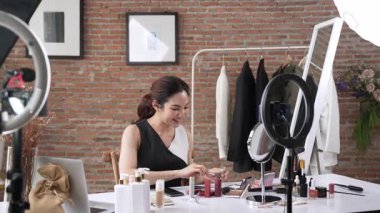 Kadın nüfuzlu kişi canlı yayın yapan video görüntülerini sosyal medya ya da blog üzerinden gözden geçiriyor. Kozmetik stüdyosu ışıklandırmalı mutlu genç kız çevrimiçi pazarlama oturumu yayını için..