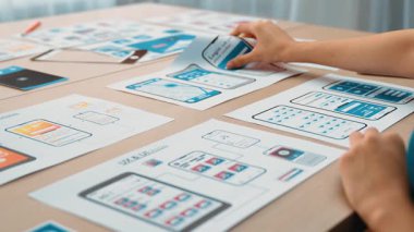 Mobil uygulama için kullanıcı arayüzü prototipi ya da masadaki program modeliyle birlikte web sitesi planlaması yapan bir şirket çalışanı. UX UI tasarımcısı kullanıcı dostu arayüz planını dikkate alır. Sinerjik