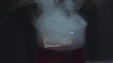 Kapanış barmeni dumanlı kokteyl bardağının dönüşümlü açılış sisi üzerine dilimlenmiş limon süslemesi alkol serinletici vitrine odaklanmada reklam için özel içecek listesi yapıyor. Vinosity.