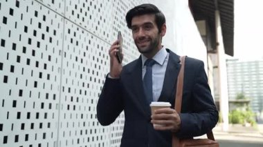 İş adamı telefona cevap verir ve iş yatırımları hakkında konuşur. İş planı, pazarlama stratejisi ya da çalışma hakkında konuşmak için akıllı telefonla konuşurken sokakta yürüyen mutlu bir yönetici. Sevinçli..